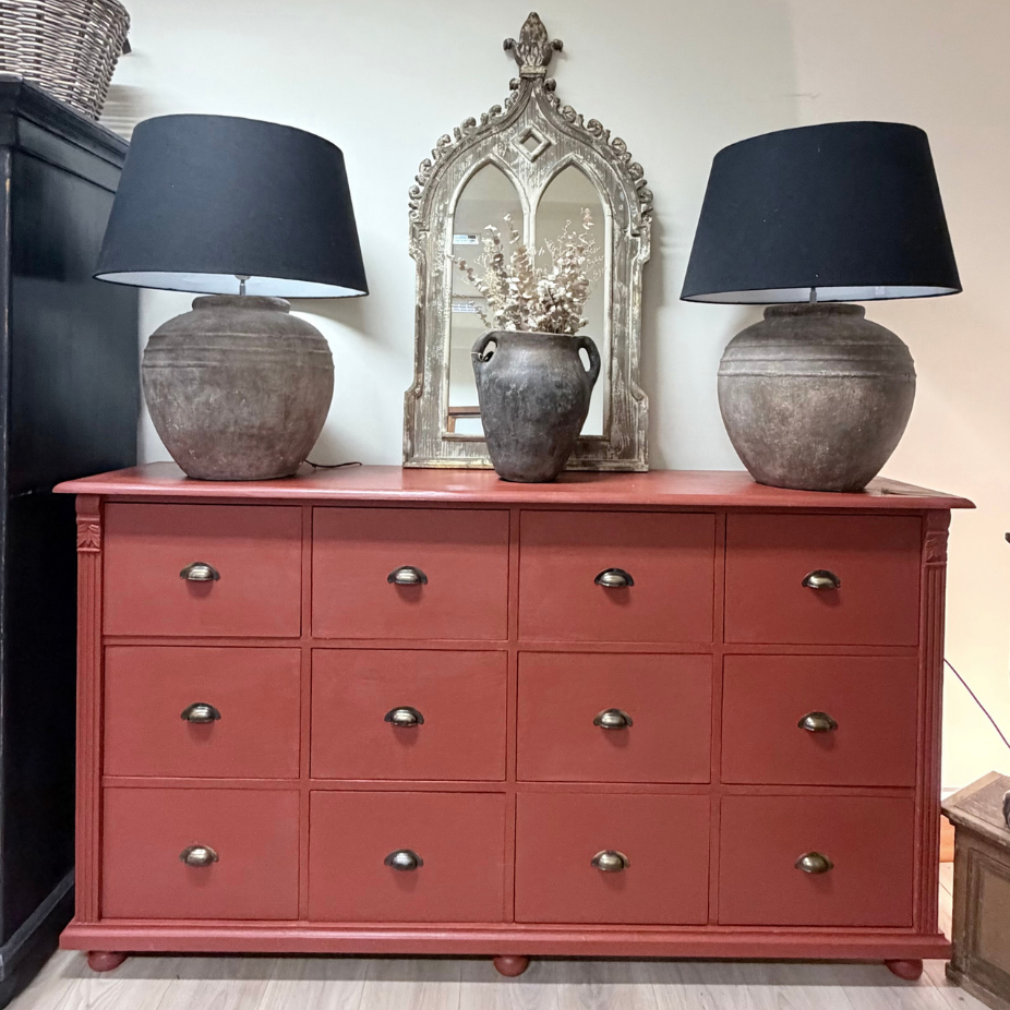 Large red farmhouse storage unit in a luxury country living room, showcasing its architectural proportions and heirloom quality.