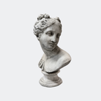 Classical female bust in aged cast stone, three-quarter profile with pinned wavy hair, on turned pedestal base